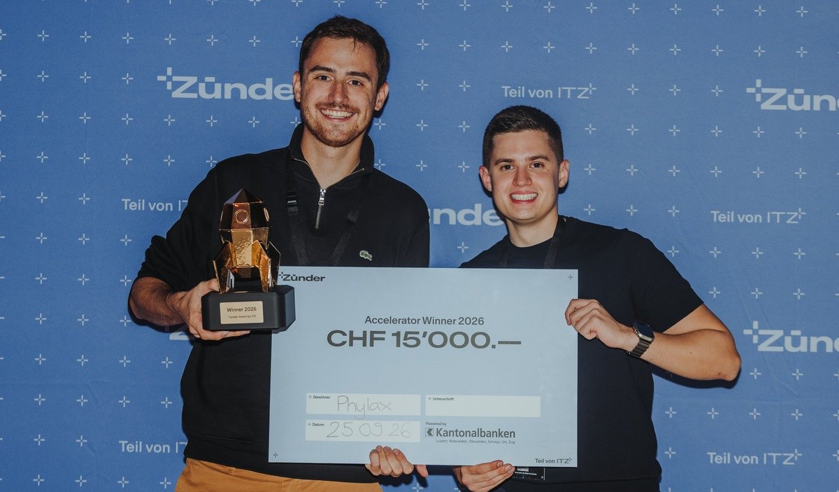 Georg M. V. Olowson, Chairman and CEO, and Janik Bücher, CTO, holding the *zünder Award 2026 trophy and the CHF 15,000 Accelerator Winner 2026 cheque
