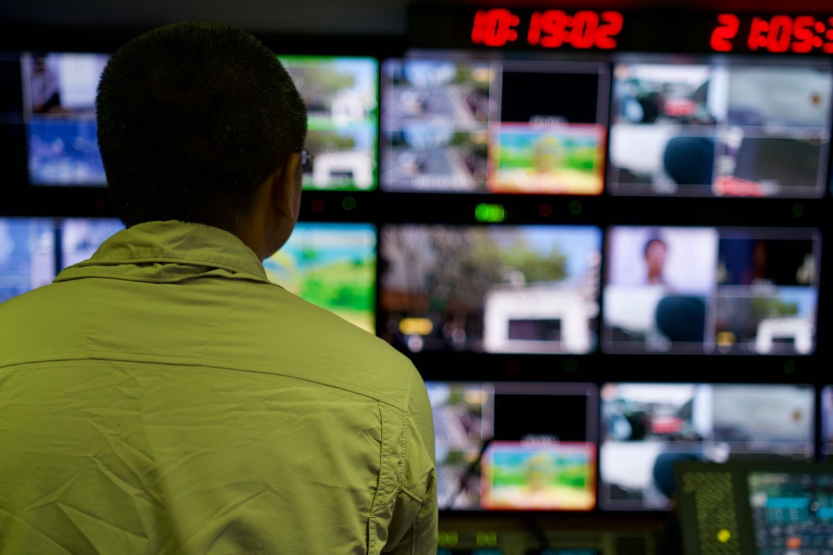 Operator overseeing a wall of monitors in a dark control room