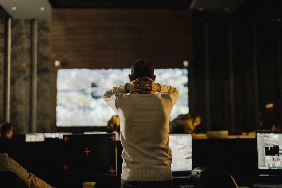 Person standing thoughtfully in a dimly lit control room